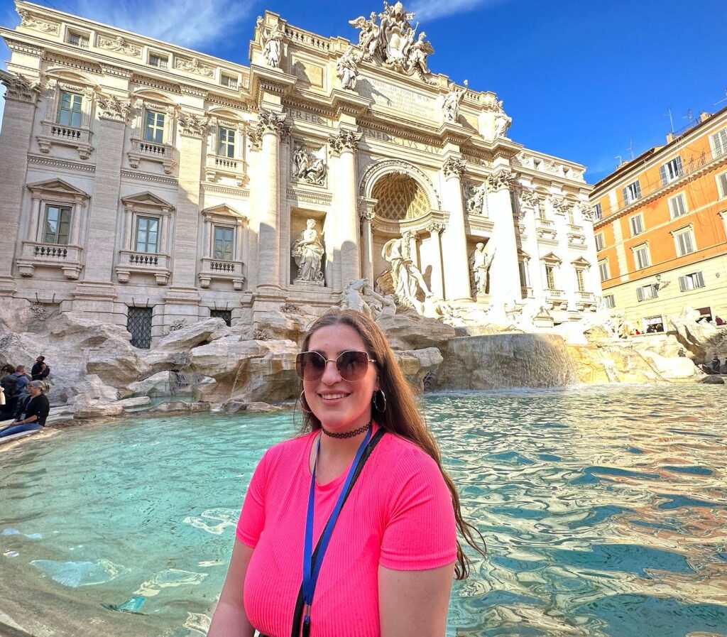 Una persona con la Fontana Di Trevi en Roma, de fondo a su espalda,
