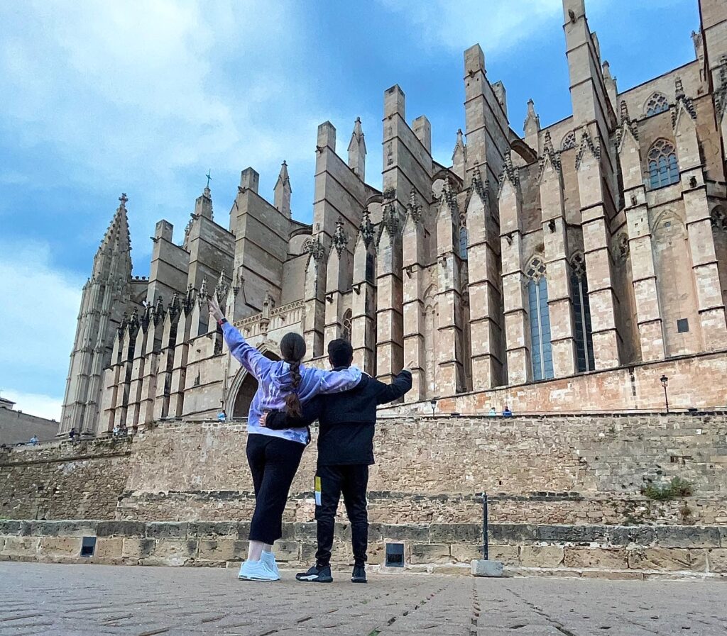 Dos personas con la catedral de Palma de Mallorca de fondo (parada del Crucero Costa Toscana)