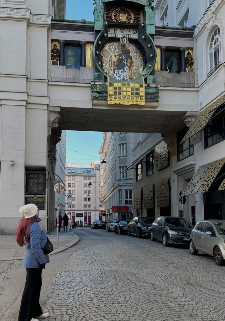chica en la calle delante del reloj de Anker en Viena